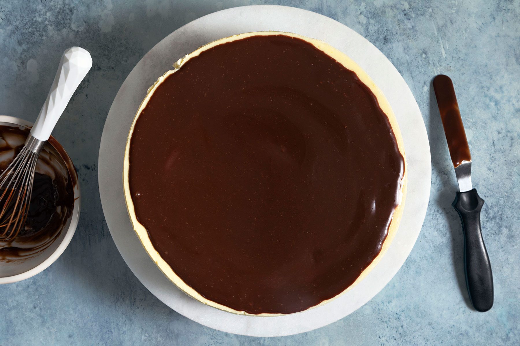 Spreading chocolate ganache over baked cheesecake