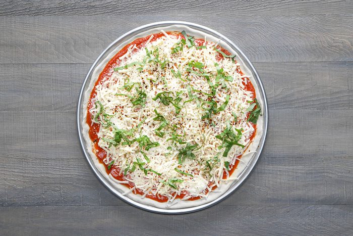 Spread the topping on the crust and top it up with mozzarella and Romano cheeses, basil, oregano and pepper flakes
