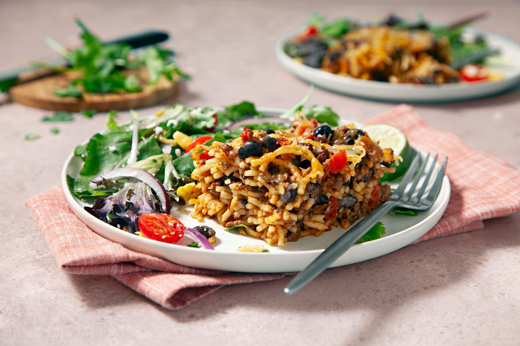 Taco Spaghetti in a plate on a table cloth placed on a wooden surface