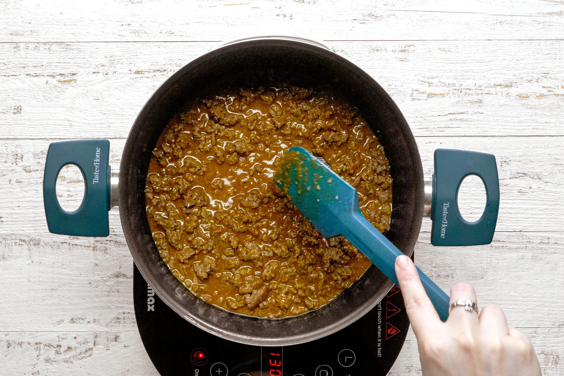 Cooking beef in a dutch oven using a spatula to stir the beef