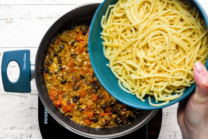 Combining the spaghetti with beef mixture in a dutch oven