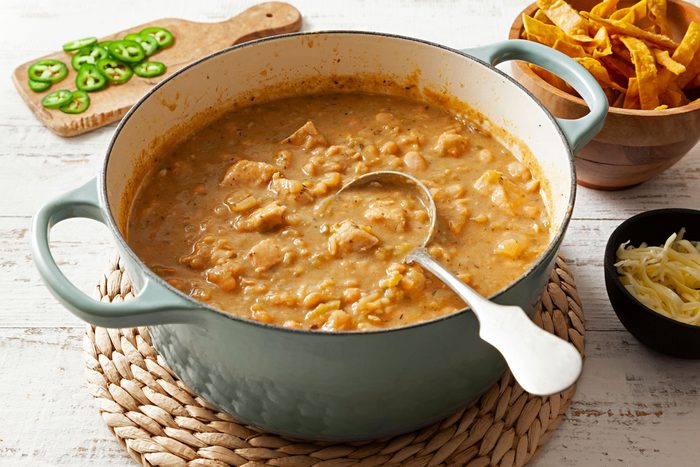 White Chicken Chili served in a large on a with chips on a wooden table