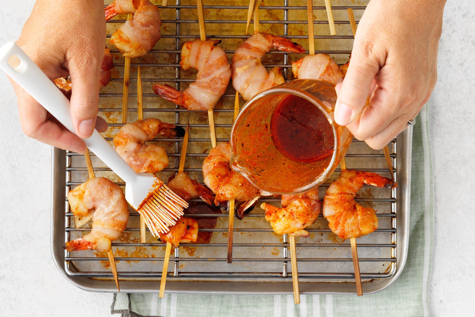 A person putting sauce on food on a grill