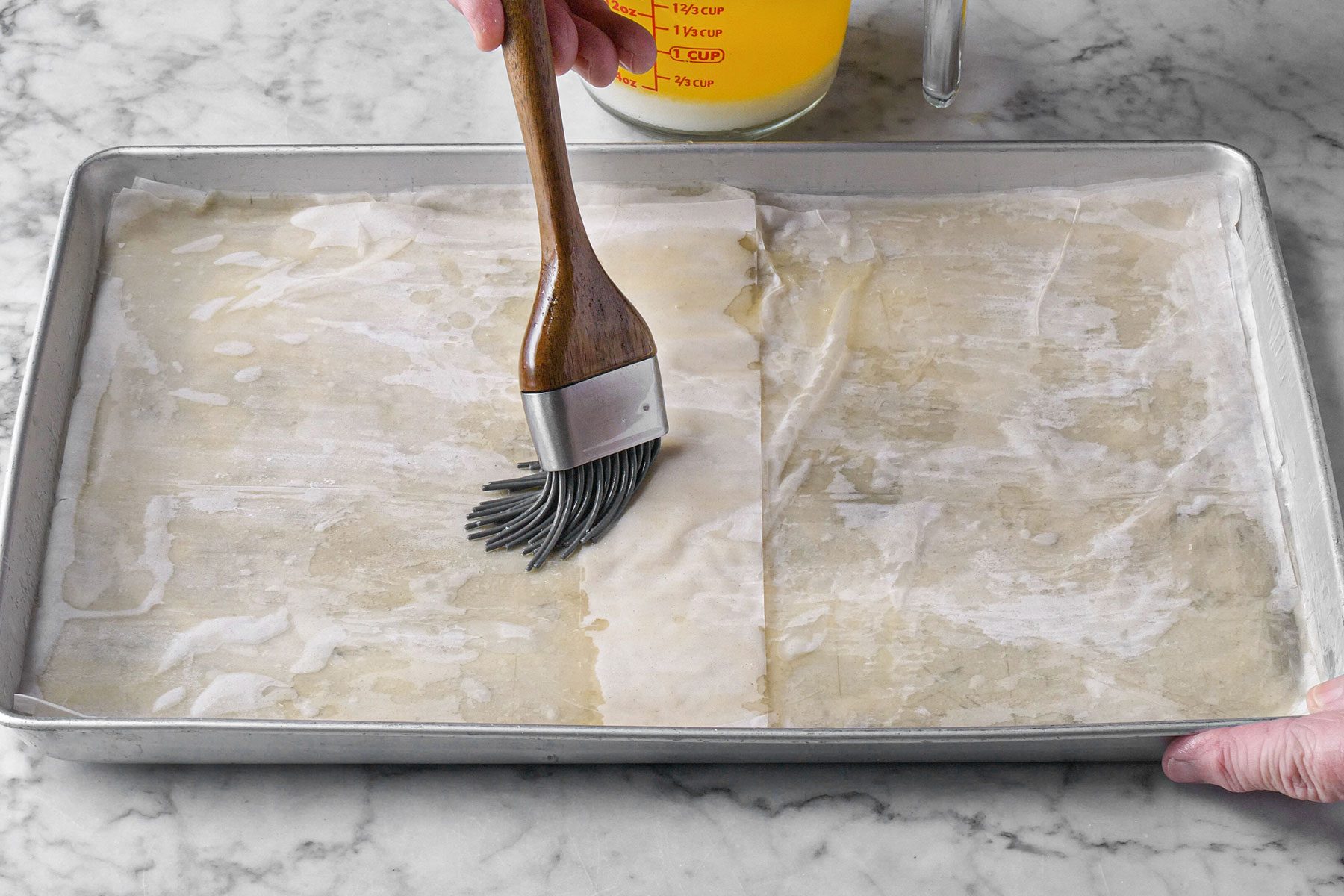 Brushing the sheets with butter