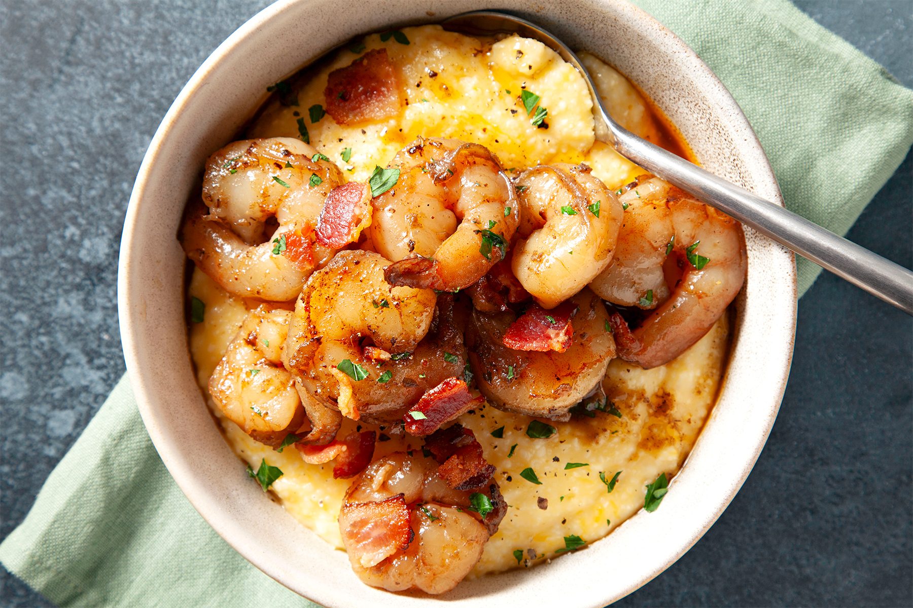 A bowl of cheesy cajun shrimp and grits with a spoon