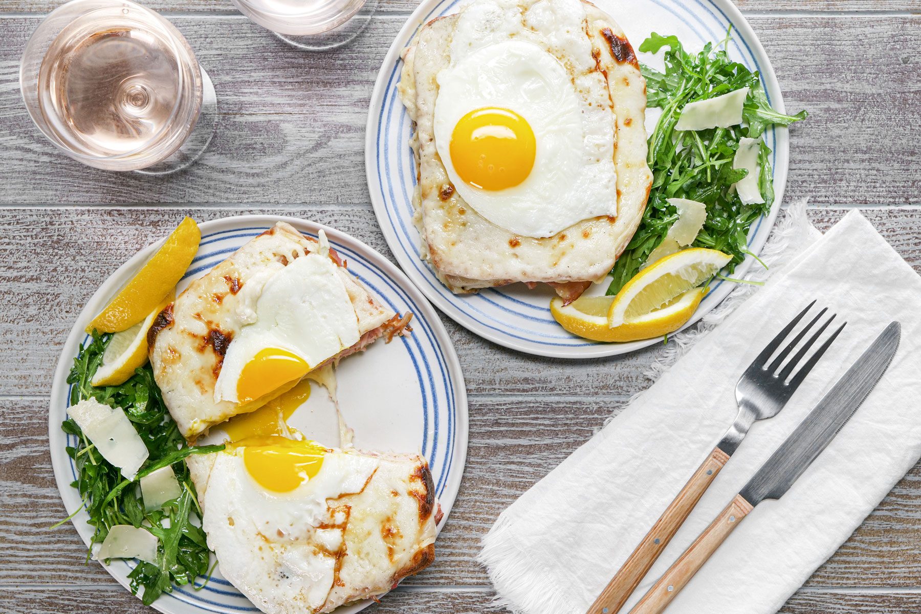 Croque Madame served in on a wooden table with fork and knife