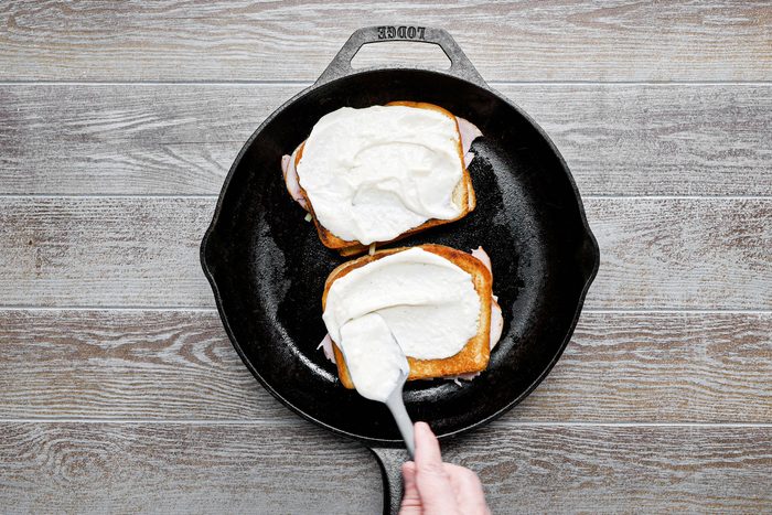 Spreading the sauce over the toasted bread on a large skillet