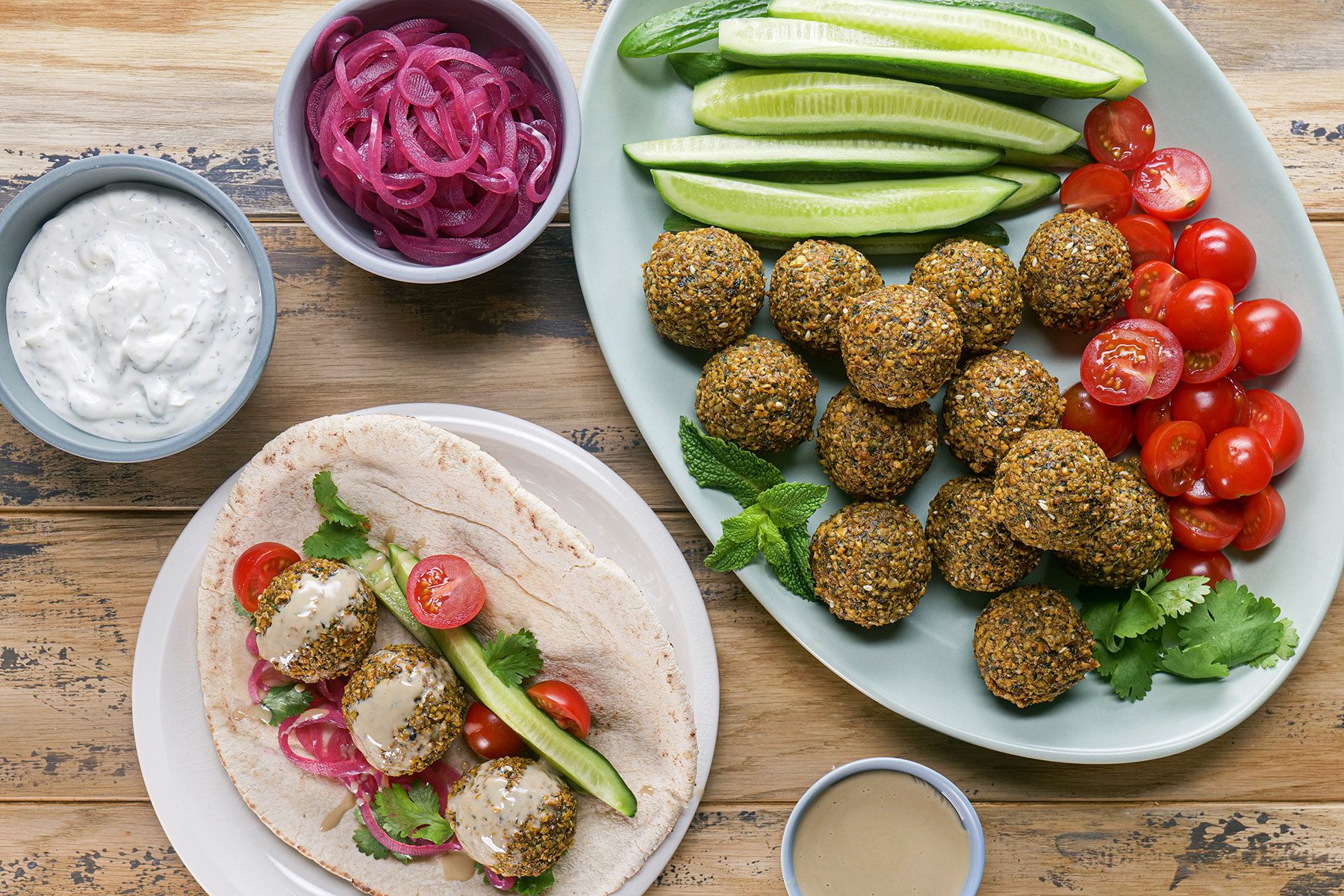 Falafel served on pita bread with sauce and vegetables on top with dip and onions on side