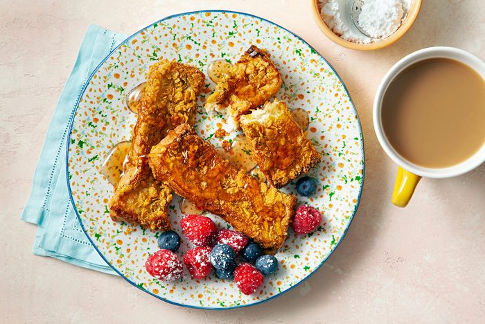Served French Toast Sticks on plate with syrup drizzled over it with tea on the side