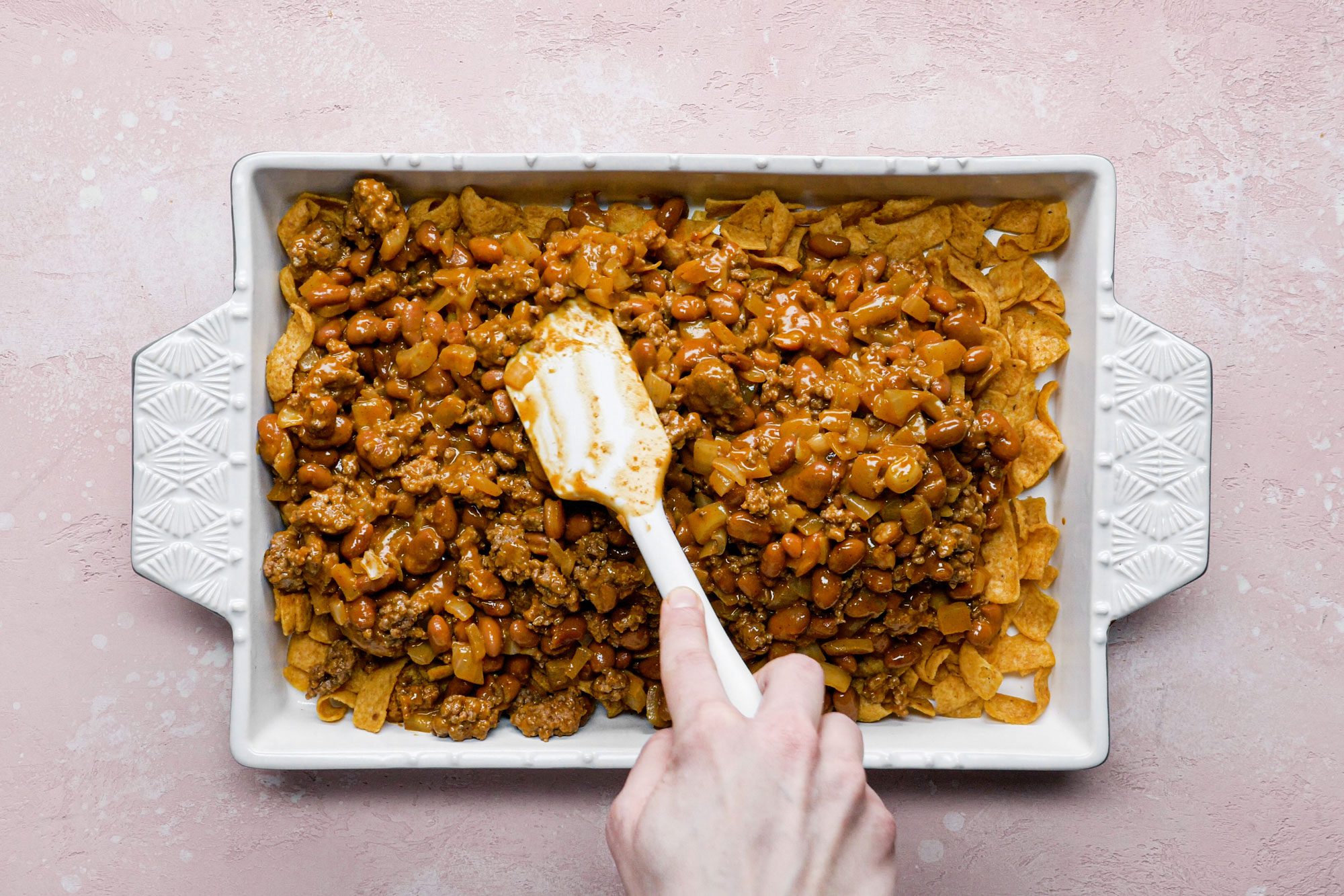 Spoon the meat and bean mixture over the top of the chips completely in the baking dish