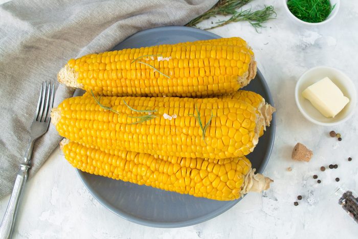 grilled corn, boiled corn on a wooden white plate. Vegetarian food, healthy food.