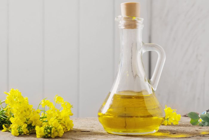 rapeseed oil (canola) and rape flowers on wooden table