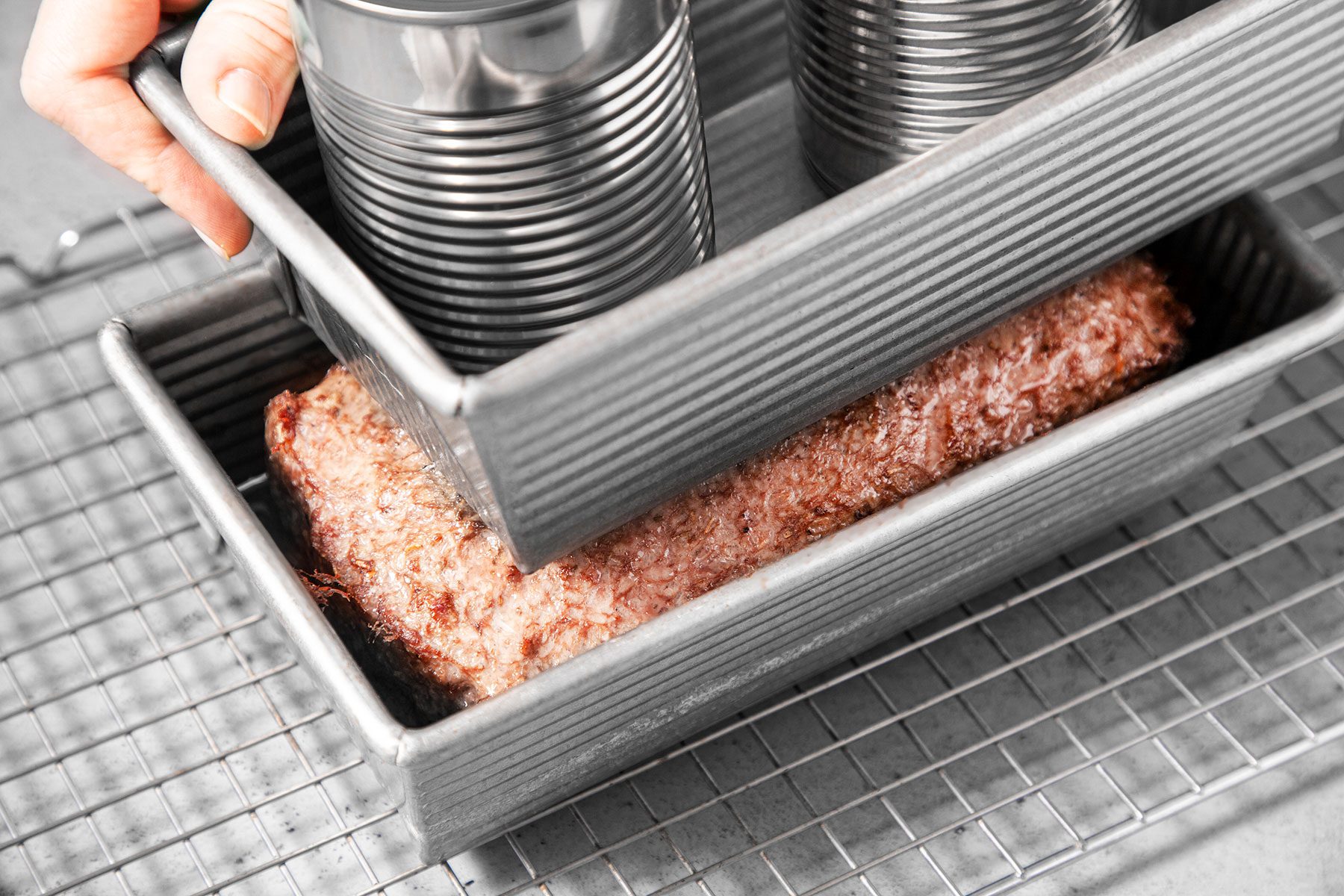 Weighing down meat with another utensil