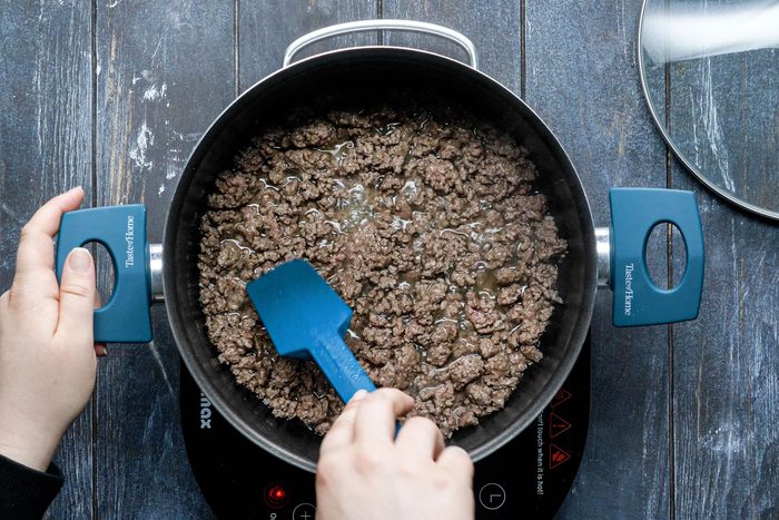 Cooking the beef in a large saucepan, stirring with a spatula