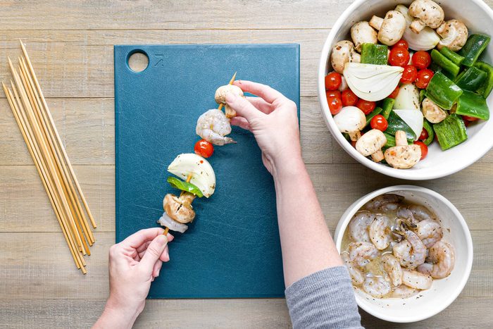 Threading the shrimp and vegetables on wooden skewers