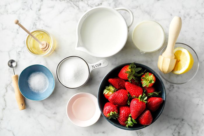 overhead shot of all ingredients for strawberry gelato on marble surface