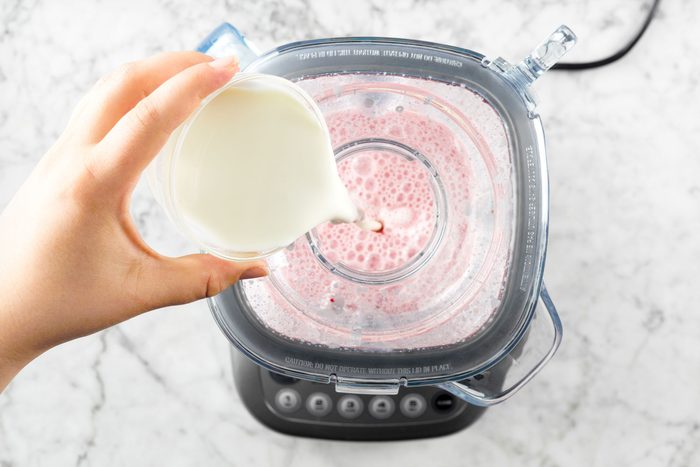 overhead shot of pouring cream into the blender; marble surface;