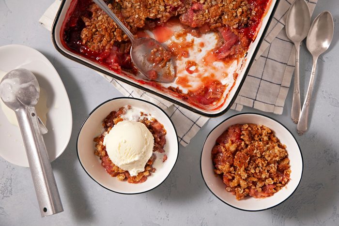 A bowl of Strawberry Rhubarb Crisp served with vanilla ice cream
