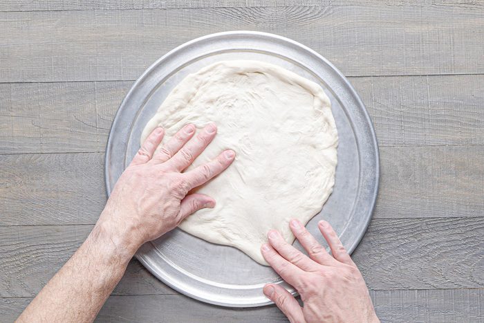 Pressing the dough on greased pan