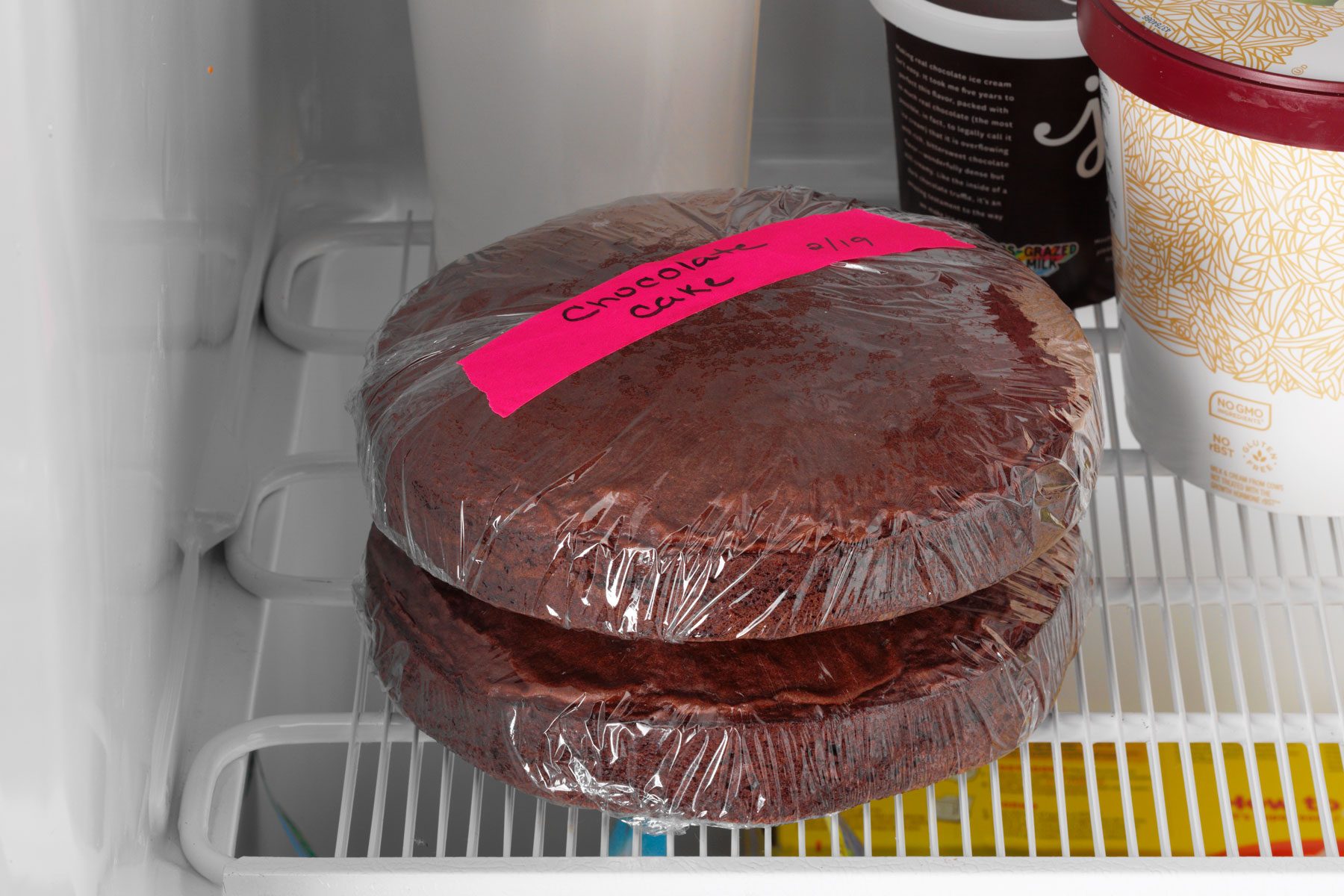 Two round layers of unfrosted chocolate cake in the freezer