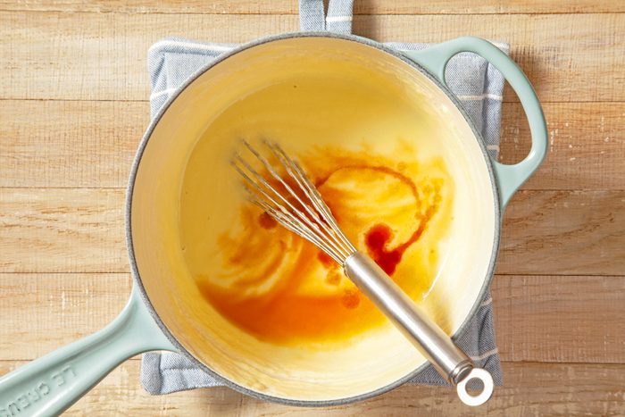 A green saucepan of liquid paste with a whisk