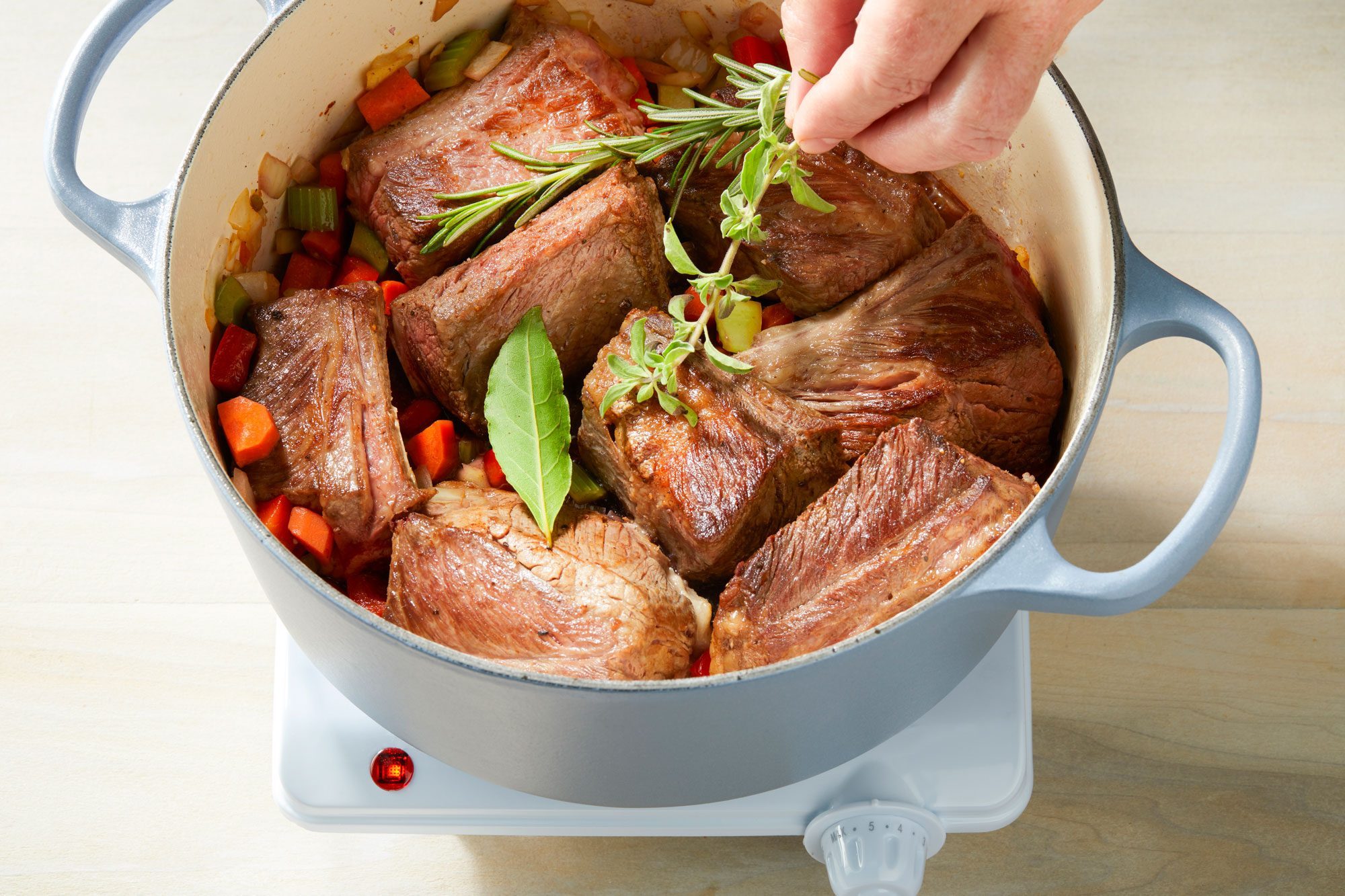 Adding herbs to Dutch oven after ribs have been returned and beef broth has been added