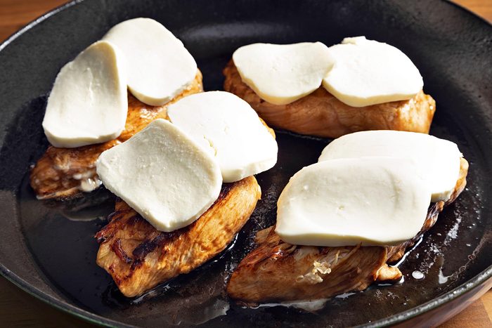 Close shot of ovenproof skillet; top with cheese; brown wooden background;