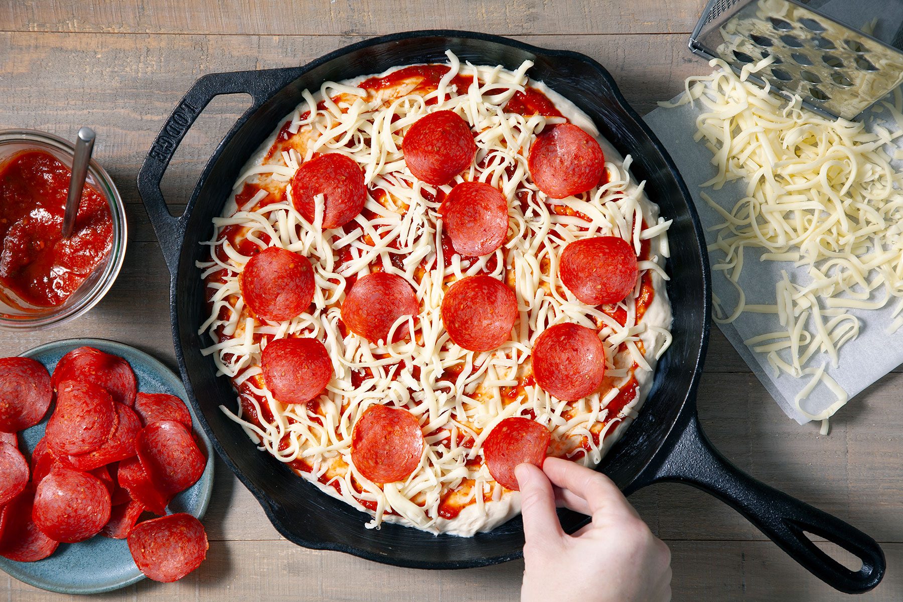 Topping the dough with pepperoni pieces 