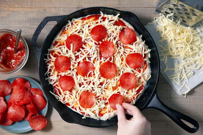 Topping the dough with pepperoni pieces