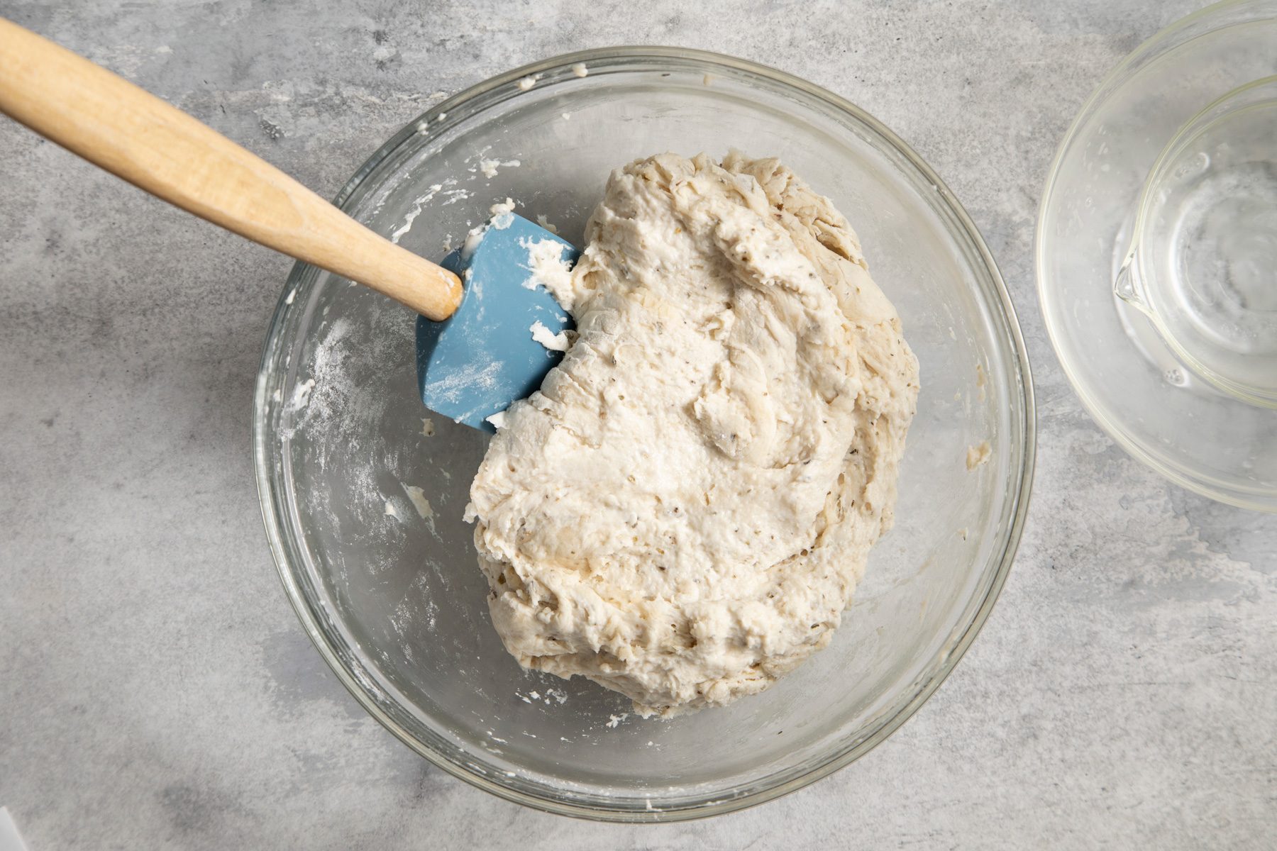 A bowl of pizza dough with a spatula