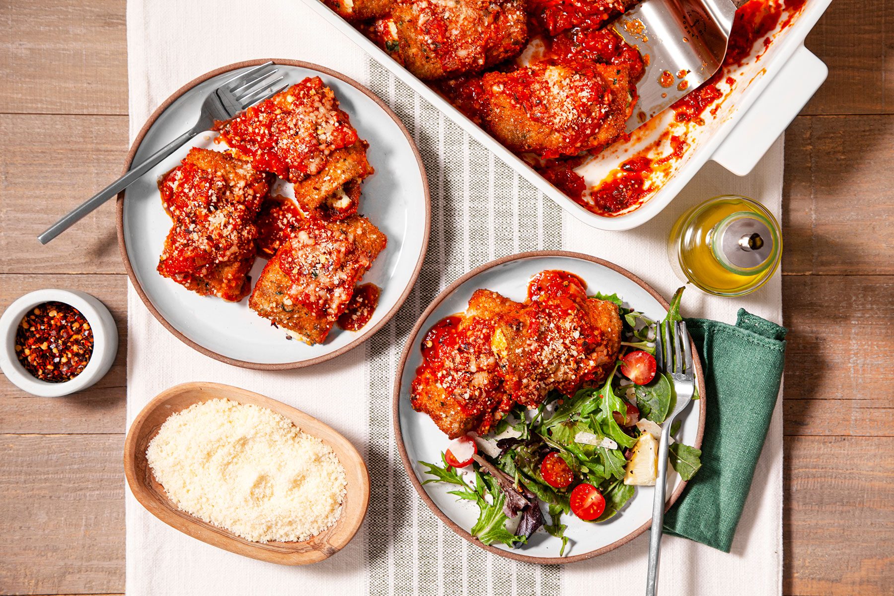 Eggplant Rollatini served on plate with vegetables with forks on side