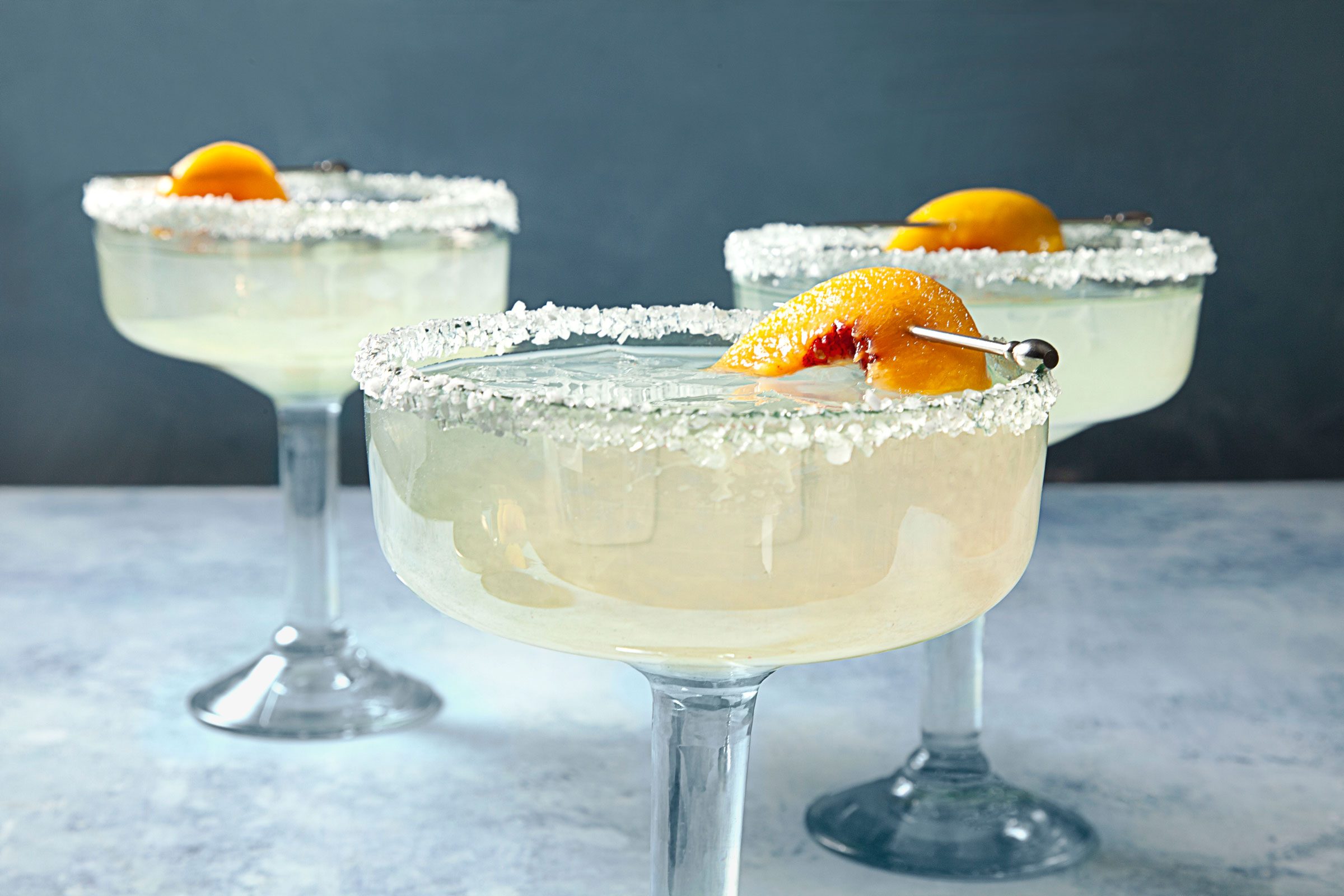three glasses with salt rims and peach margarita