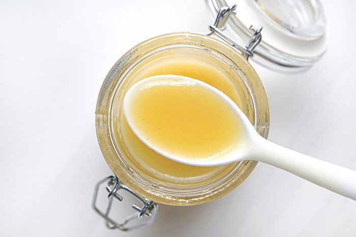 Top view shot of Fast Honey-Mustard Salad Dressing; stored in glass jar; spoon; white background;