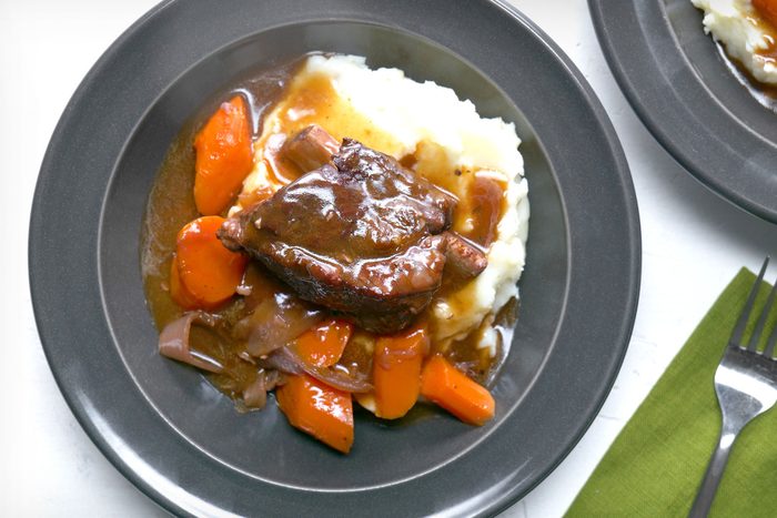 overhead shot of Instant Pot Short Ribs served on grey plate with fork on white background