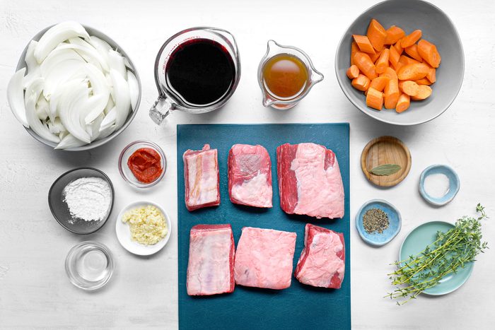 overhead shot of beef short ribs on blue chopping board with all other ingredients for Instant Pot Short Ribs on white background