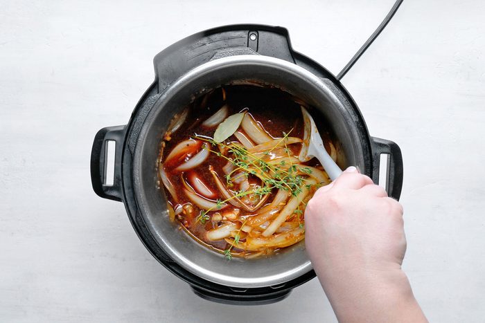 overhead shot; white background; Stir in beef broth, wine, thyme and bay leaf in pressure cooker;