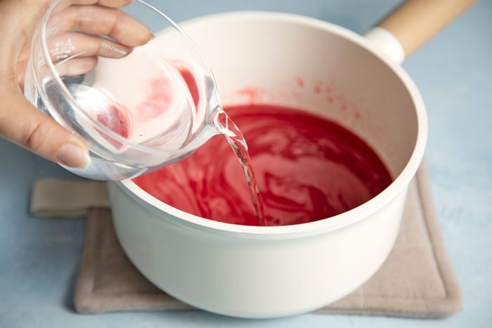 close shot of vodka added in the cherry gelatin mix