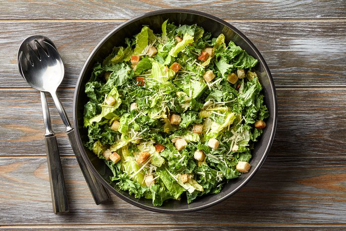A bowl of salad with croutons and cheese