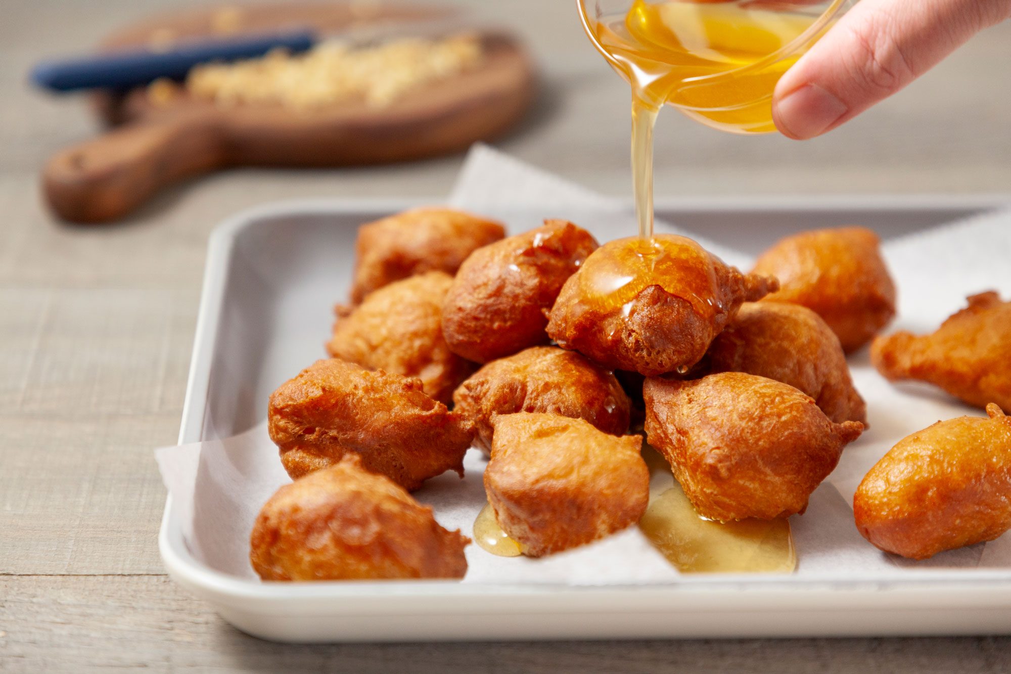Drizzle honey syrup over the doughnut balls in a serving pan