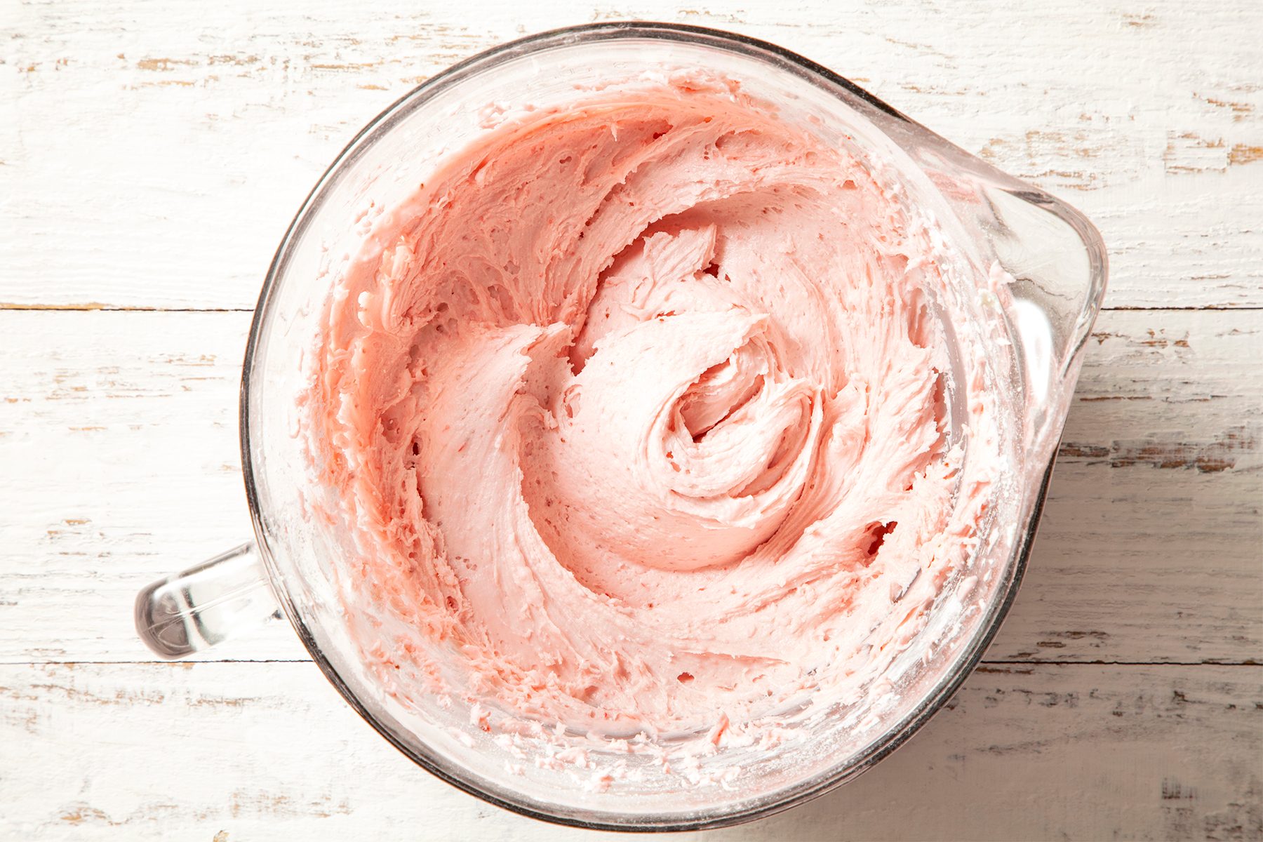 A glass container with pink frosting 