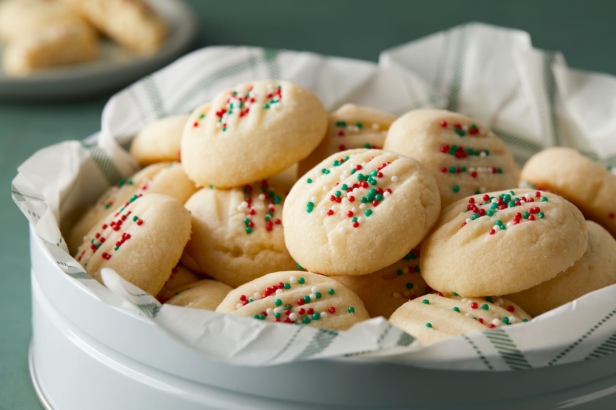 Colorful sprinkles adorn Whipped Shortbread cookies in a container