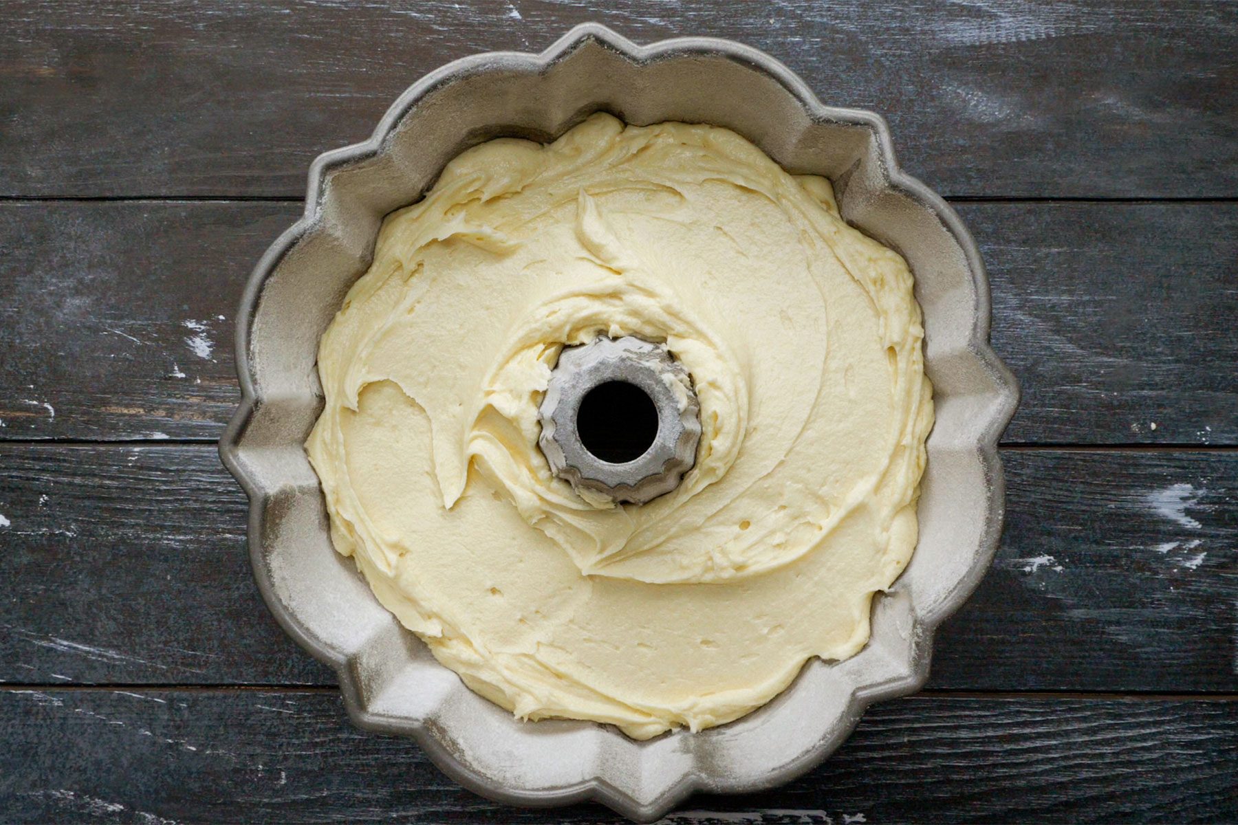 Overhead shot of transferred batter to prepared pan; dark wooden bcakground;
