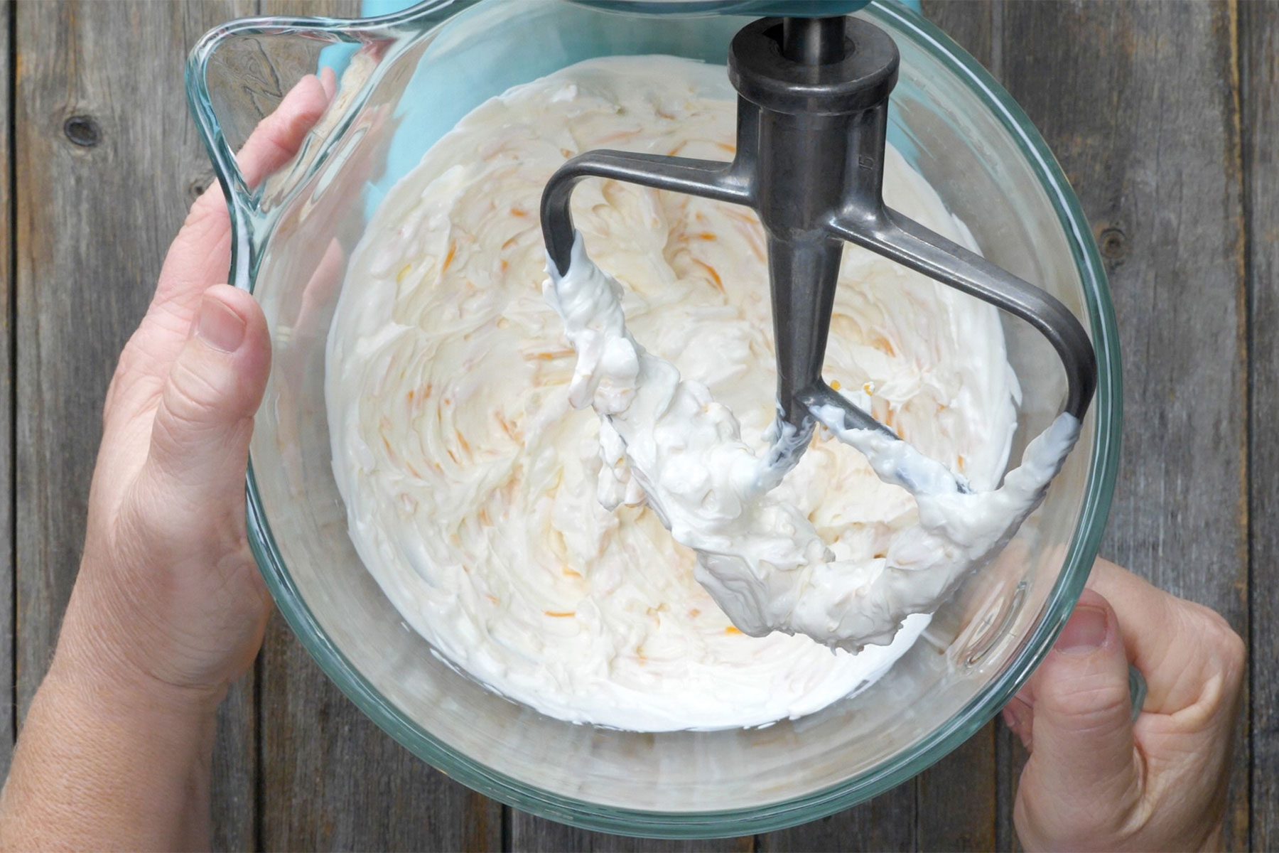 Overhead shot of beating cream cheese, cheese and sour cream until blended; wooden background;