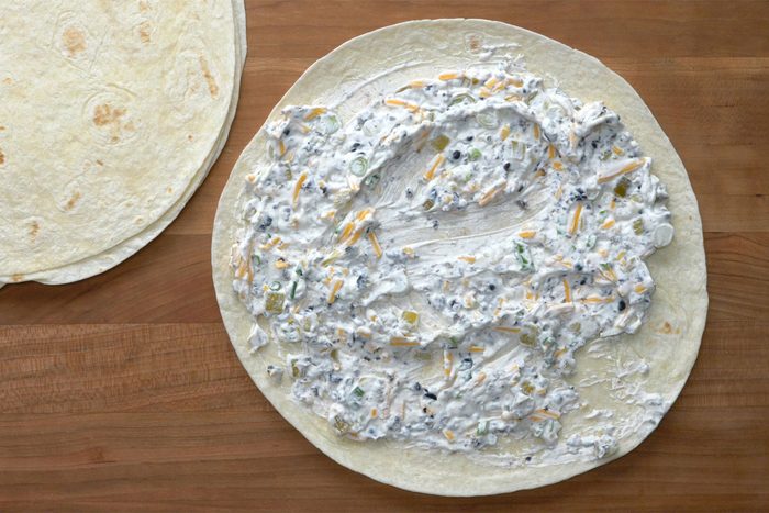 Overhead shot of spread mixture over tortillas; wooden background;