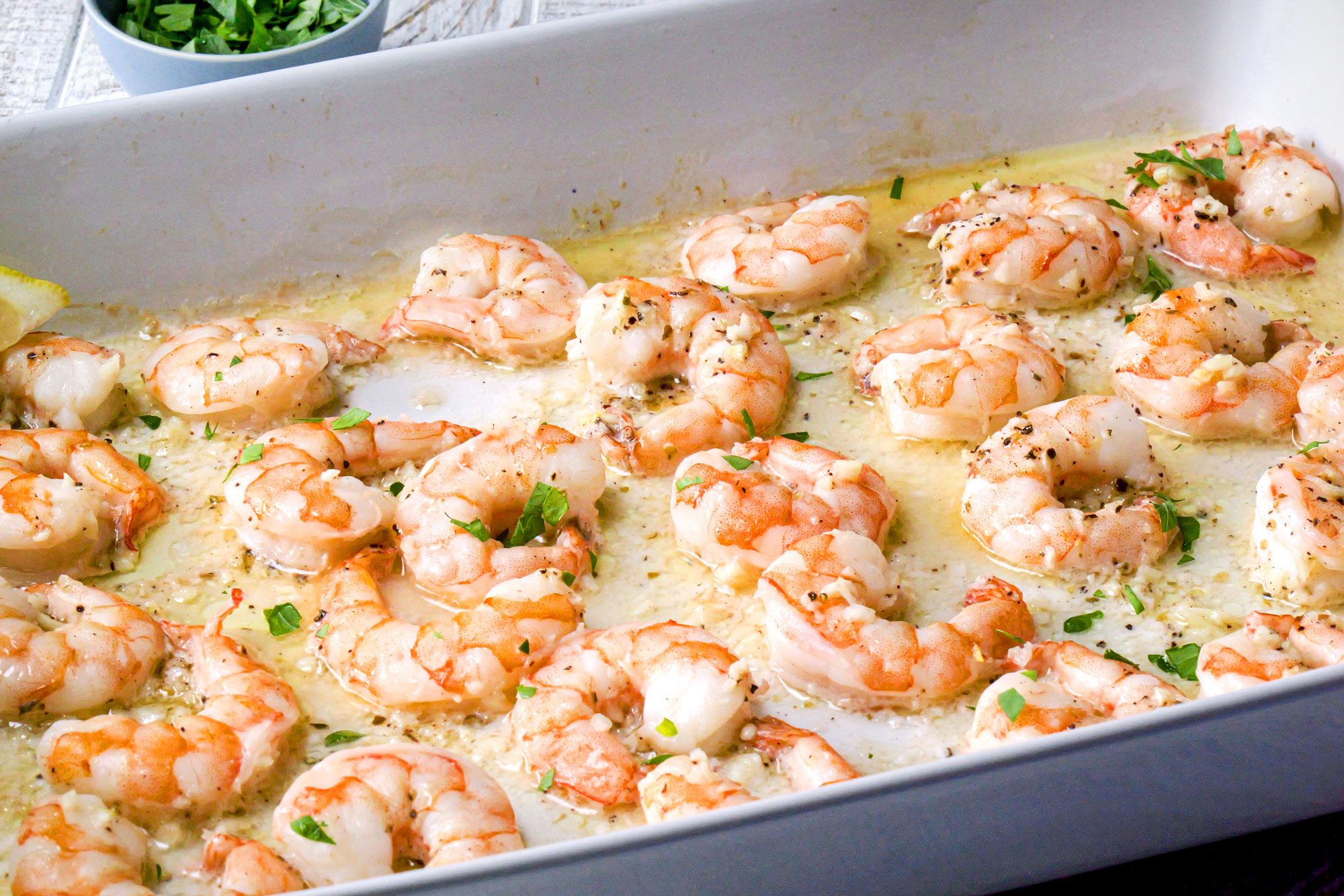 close shot of baked shrimps in white rectangular dish;