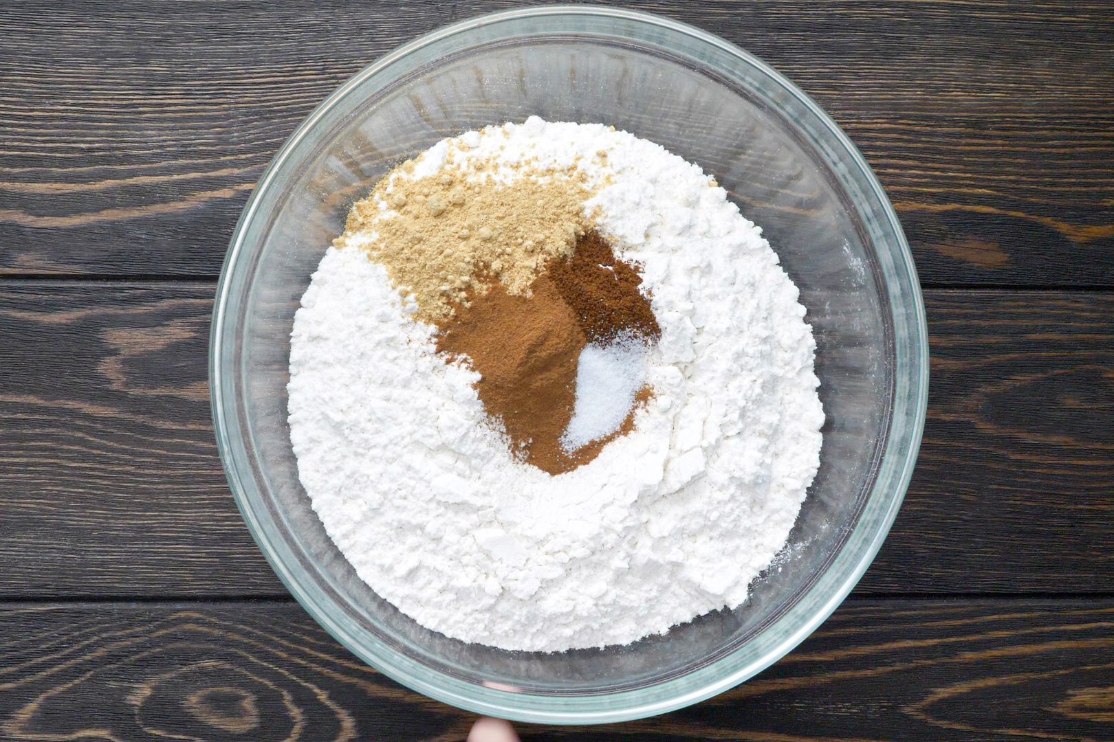 A glass bowl of dry mixture on a wooden table