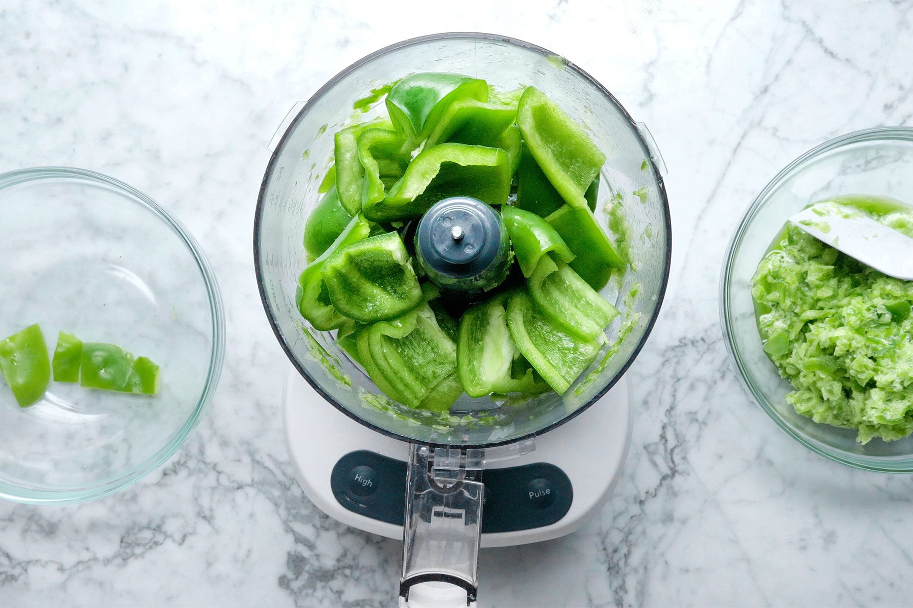 Overhead shot of pulse green peppers and onions in batches in a food processor until finely chopped; transfered in bowl; marble background;
