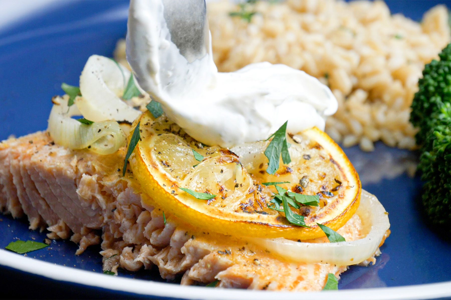 Close shot of Salmon with Creamy Dill Sauce; served on plate; with fesh veggies and rice; blue ceramic plate;