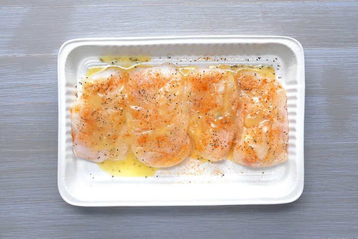 Overhead shoy of placed fish in a greased baking dish; sprinkled with seasoned salt and pepper; drizzled with butter; wooden background;