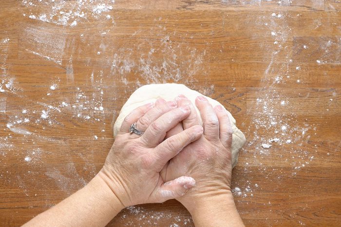 Dough kneaded by hands on a wooden surface